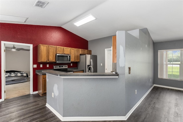 kitchen with lofted ceiling, kitchen peninsula, dark wood-type flooring, ceiling fan, and appliances with stainless steel finishes