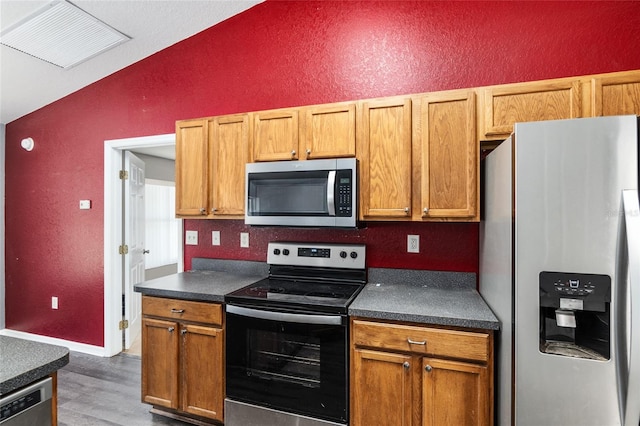 kitchen featuring stainless steel appliances, dark hardwood / wood-style floors, and vaulted ceiling