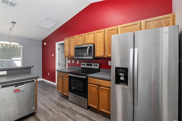 kitchen with lofted ceiling, appliances with stainless steel finishes, an inviting chandelier, hanging light fixtures, and dark hardwood / wood-style floors