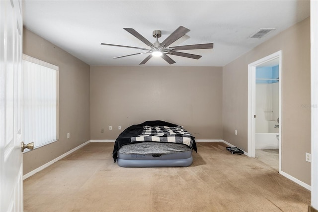 unfurnished bedroom featuring light colored carpet, ensuite bath, and ceiling fan