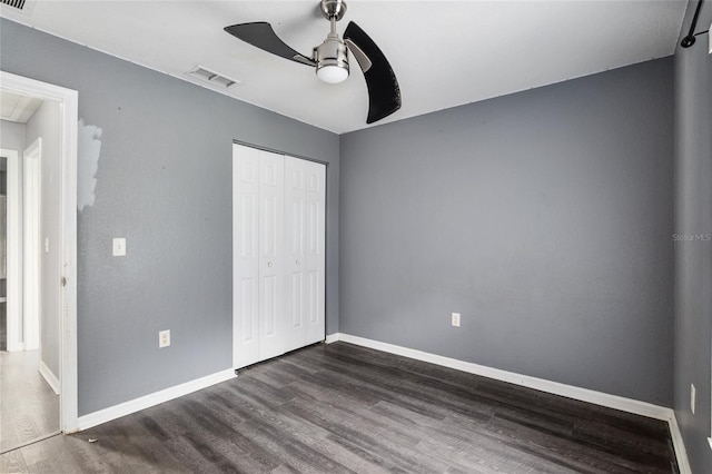 unfurnished bedroom with dark hardwood / wood-style flooring, a closet, and ceiling fan