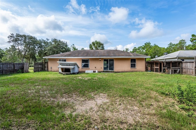 rear view of house featuring a jacuzzi and a lawn