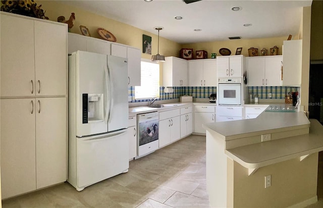 kitchen with white appliances, tasteful backsplash, kitchen peninsula, hanging light fixtures, and a breakfast bar area