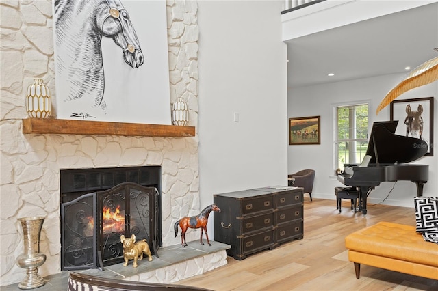 living room featuring a stone fireplace and light hardwood / wood-style floors