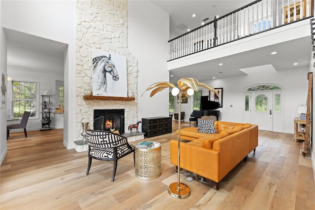 living room featuring a fireplace, light hardwood / wood-style floors, and a high ceiling