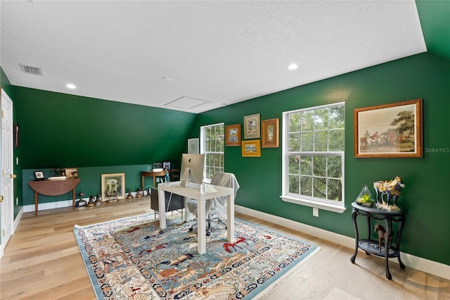 office space featuring vaulted ceiling, a textured ceiling, and light hardwood / wood-style floors