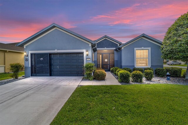 ranch-style home with a garage and a lawn