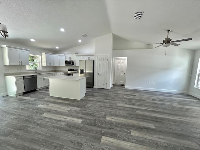 kitchen featuring ceiling fan, appliances with stainless steel finishes, a kitchen island, white cabinets, and sink