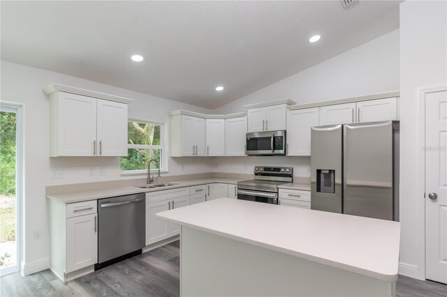 kitchen featuring vaulted ceiling, stainless steel appliances, white cabinetry, and sink