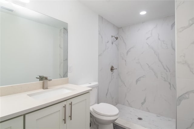 bathroom featuring toilet, vanity, and a tile shower