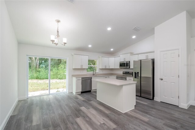 kitchen with pendant lighting, appliances with stainless steel finishes, a kitchen island, white cabinetry, and sink