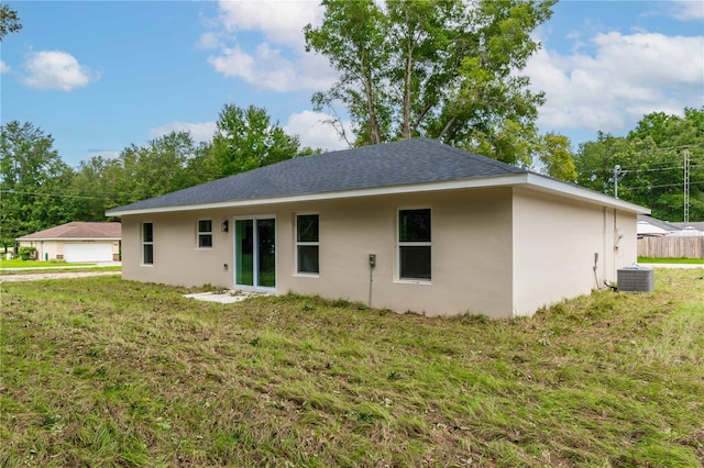 rear view of property featuring central AC and a lawn