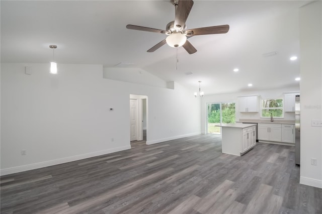 unfurnished living room with lofted ceiling, dark hardwood / wood-style floors, and ceiling fan with notable chandelier