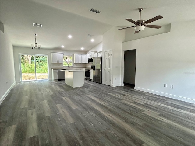 kitchen with white cabinetry, appliances with stainless steel finishes, decorative light fixtures, vaulted ceiling, and a kitchen island