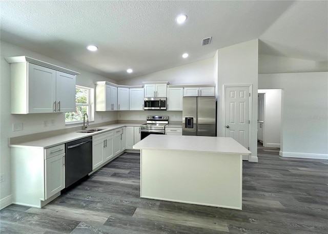 kitchen featuring a center island, white cabinetry, stainless steel appliances, sink, and vaulted ceiling