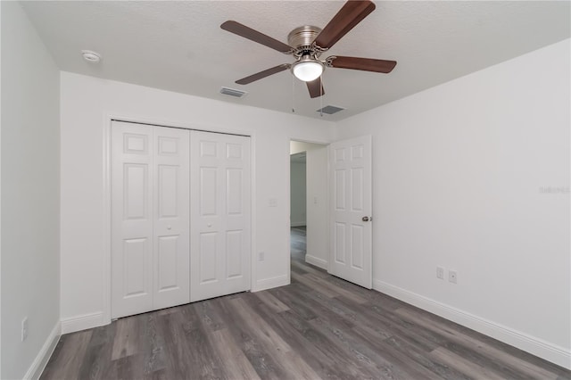 unfurnished bedroom with ceiling fan, a closet, dark hardwood / wood-style floors, and a textured ceiling