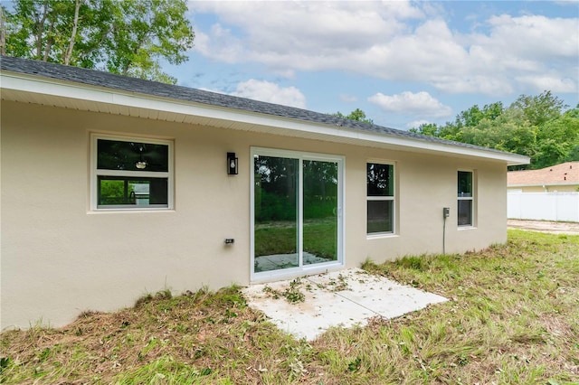 rear view of property featuring stucco siding, fence, and a patio