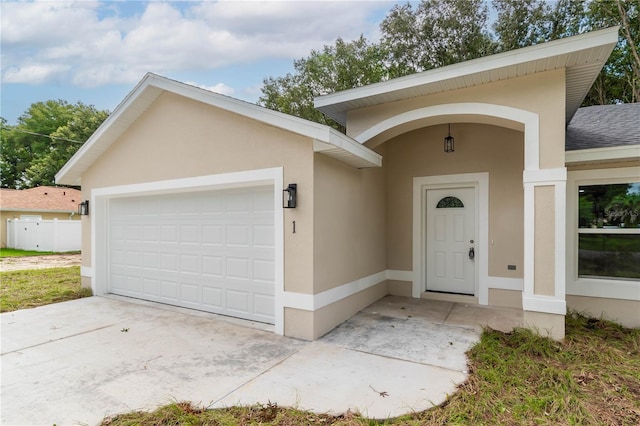 view of front of home with stucco siding, a shingled roof, a garage, and driveway