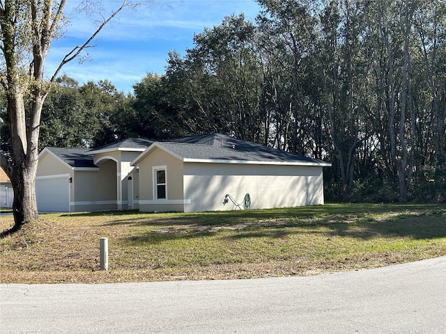 ranch-style home with an attached garage, a front lawn, and stucco siding
