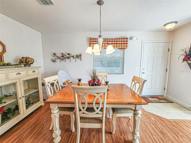 dining area featuring a textured ceiling, hardwood / wood-style flooring, and a chandelier