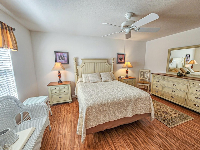 bedroom with a textured ceiling, ceiling fan, and hardwood / wood-style floors