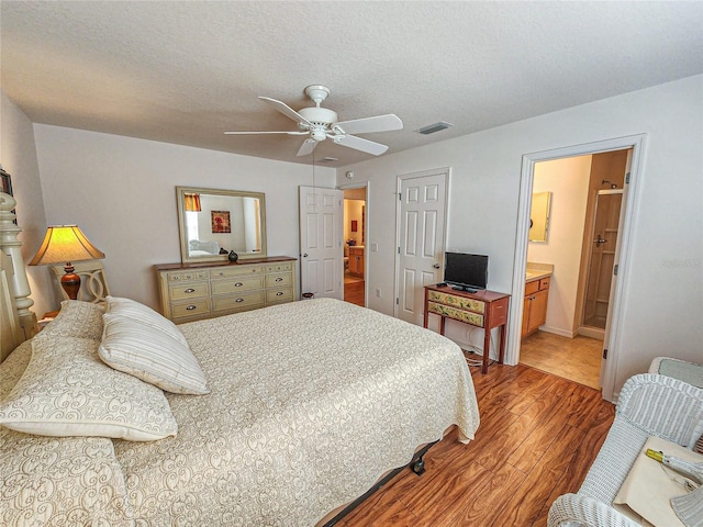 tiled bedroom with a textured ceiling, ensuite bath, and ceiling fan