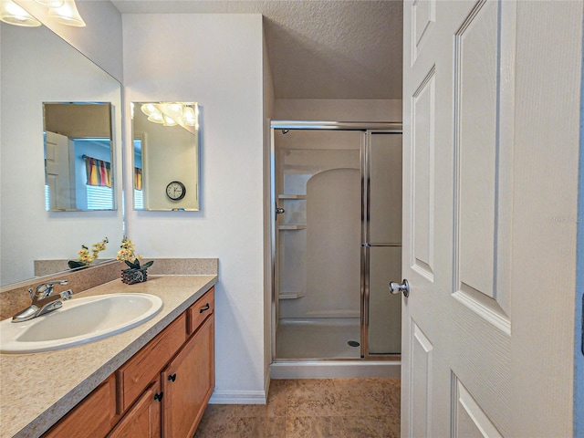 bathroom with a shower with shower door, vanity, a textured ceiling, and tile patterned flooring