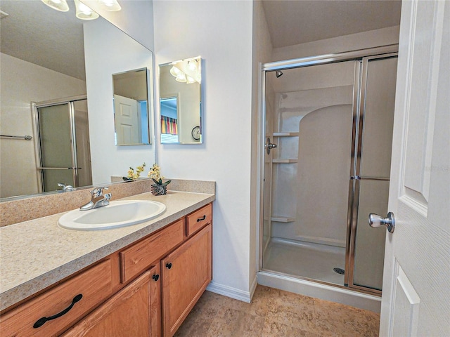 bathroom with a shower with shower door, vanity, and tile patterned floors