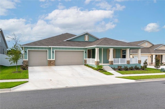 view of front of home with a garage, a front yard, and covered porch