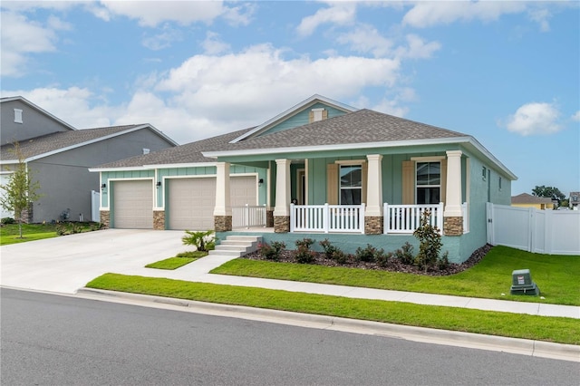 view of front of property with covered porch, a garage, and a front yard