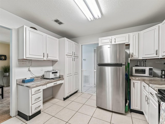 kitchen featuring white cabinets, appliances with stainless steel finishes, a textured ceiling, and light tile patterned floors