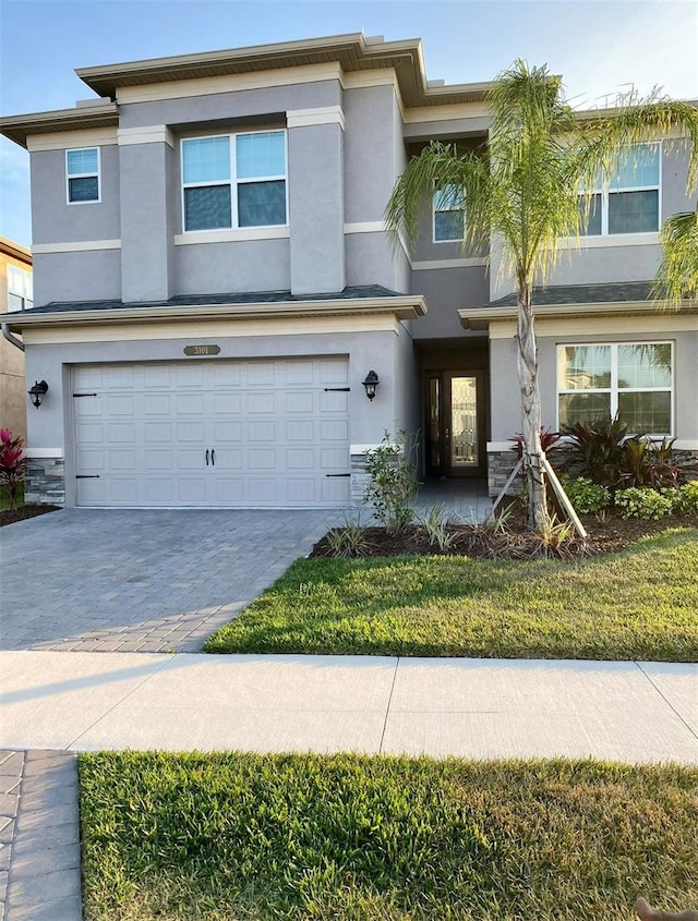 view of property featuring a garage, central AC unit, and a front lawn