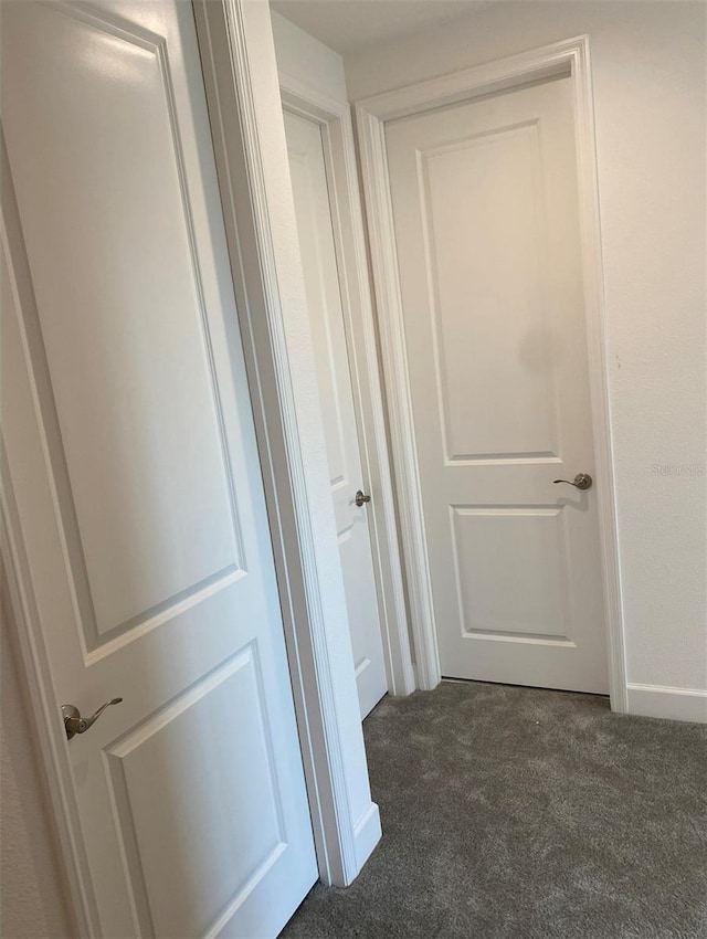 hallway featuring dark colored carpet