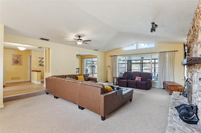 living room with a fireplace, a textured ceiling, lofted ceiling, light colored carpet, and ceiling fan