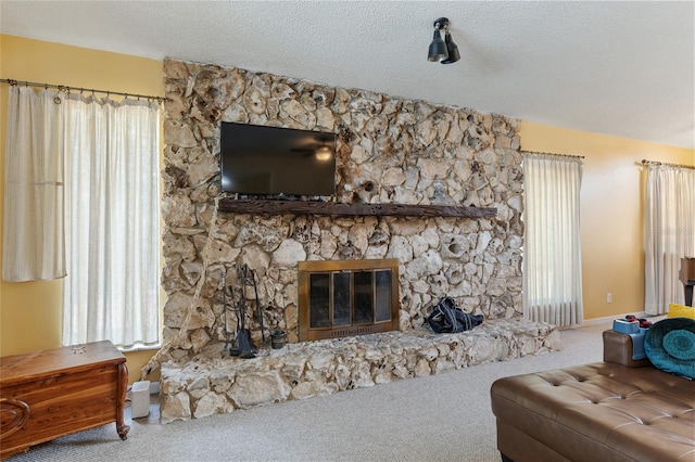 living room featuring a stone fireplace, a textured ceiling, and carpet flooring