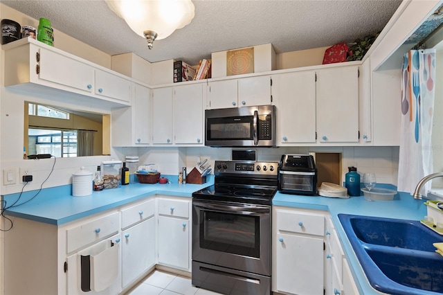 kitchen with tasteful backsplash, white cabinets, appliances with stainless steel finishes, sink, and light tile patterned flooring