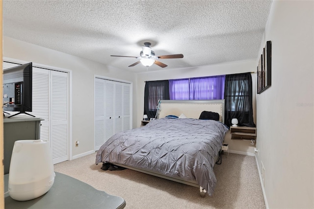 carpeted bedroom with a textured ceiling, ceiling fan, and two closets