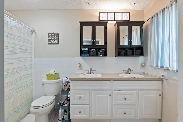 bathroom featuring dual vanity, tasteful backsplash, a textured ceiling, tile walls, and toilet