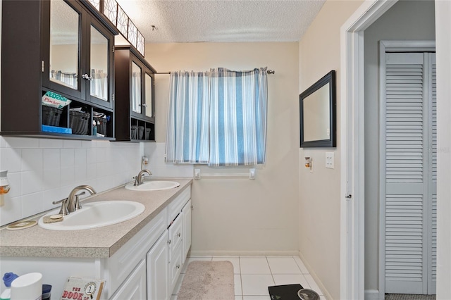 bathroom with tile patterned flooring, a textured ceiling, double sink vanity, and tasteful backsplash