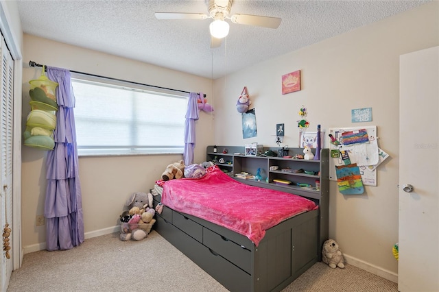 carpeted bedroom with ceiling fan, a closet, and a textured ceiling