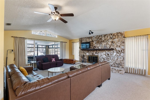 carpeted living room with ceiling fan, vaulted ceiling, a textured ceiling, and a fireplace