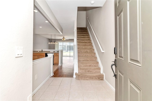 stairs with tile patterned flooring, sink, and ceiling fan