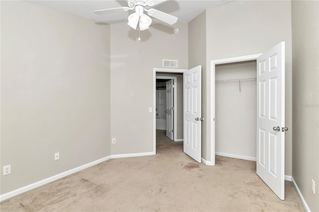 unfurnished bedroom with light carpet, ceiling fan, and a towering ceiling