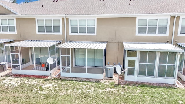 rear view of house with a sunroom, cooling unit, and a lawn