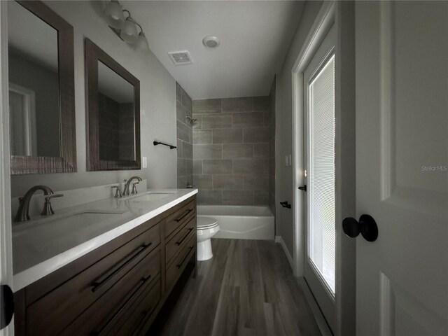 full bathroom featuring vanity, toilet, hardwood / wood-style flooring, and tiled shower / bath