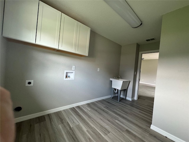 clothes washing area featuring hookup for a washing machine, wood-type flooring, hookup for an electric dryer, and cabinets