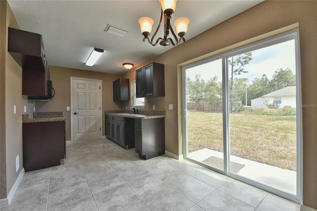 kitchen featuring a chandelier, light tile patterned floors, a textured ceiling, hanging light fixtures, and sink