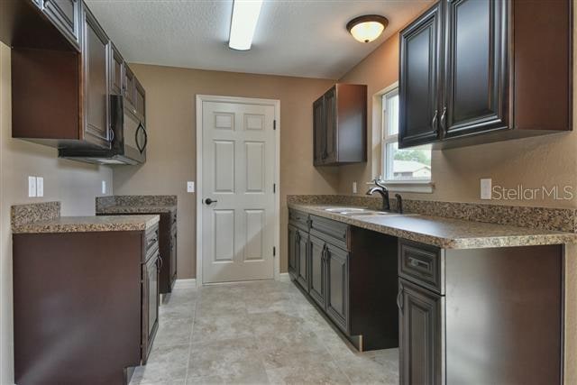 kitchen with dark brown cabinetry, sink, and light tile patterned floors