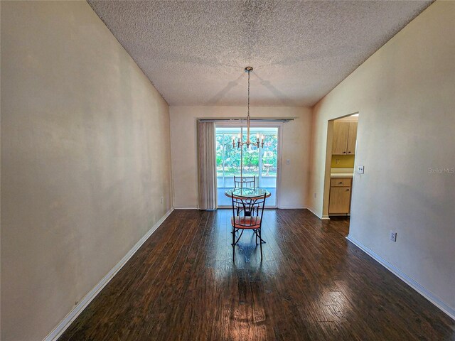 unfurnished dining area with an inviting chandelier, a textured ceiling, lofted ceiling, and dark wood-type flooring