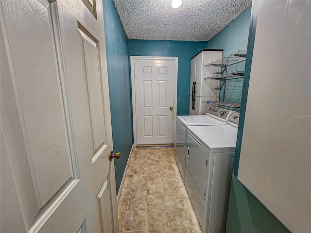 washroom with washer and clothes dryer, a textured ceiling, and light tile patterned floors